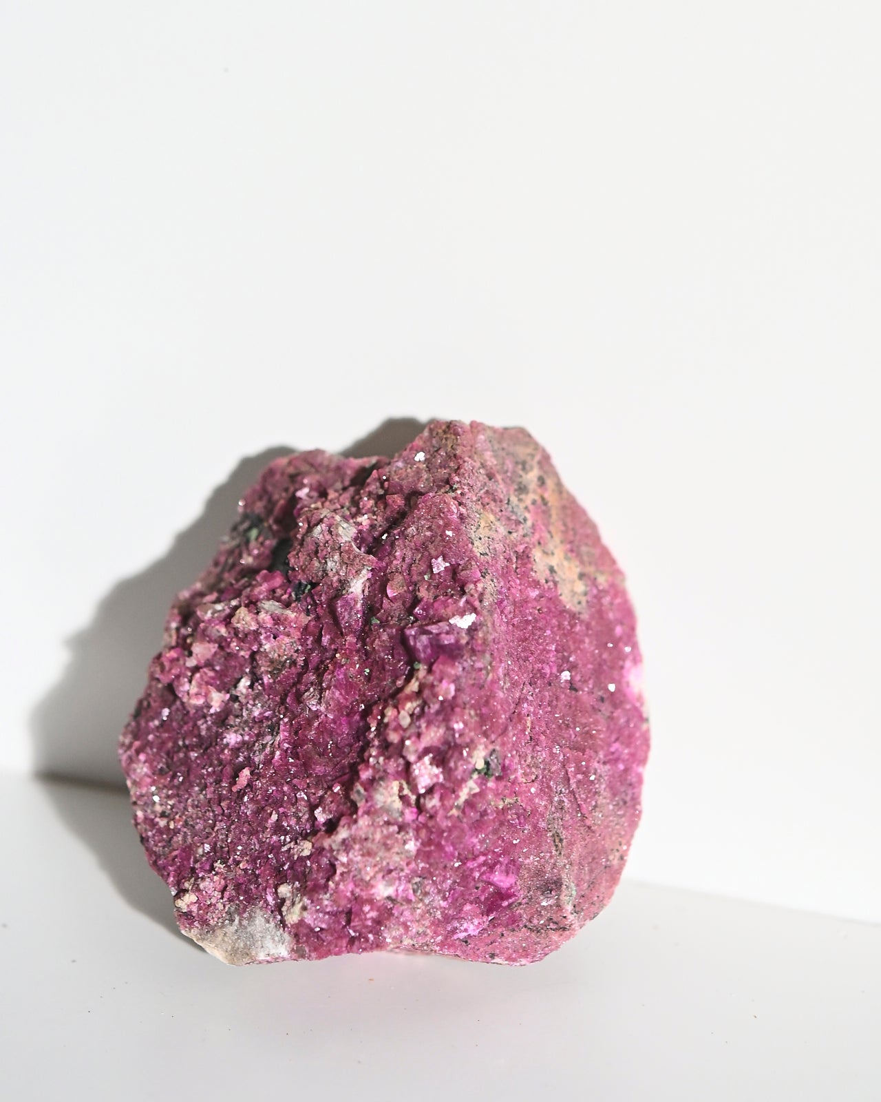 A rough, pink Cobaltoan Calcite crystal cluster on a light background.