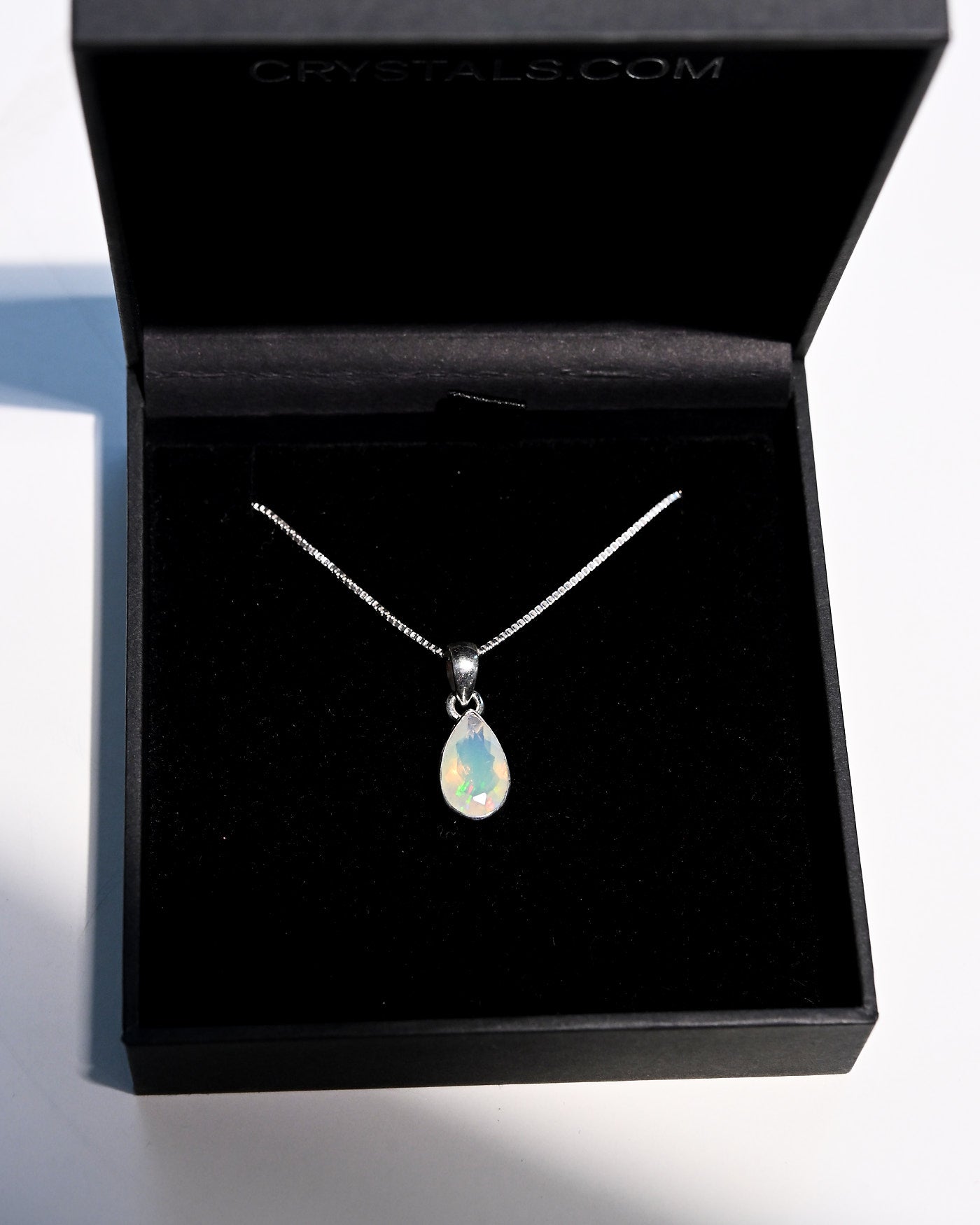 Natural opal pendant close up showing play of color green and gold flash