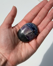 Hand holding a purple stone against a white background