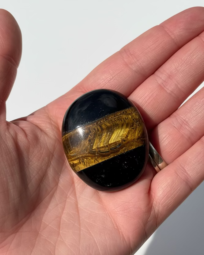 Hand holding a multicolored stone against a white background