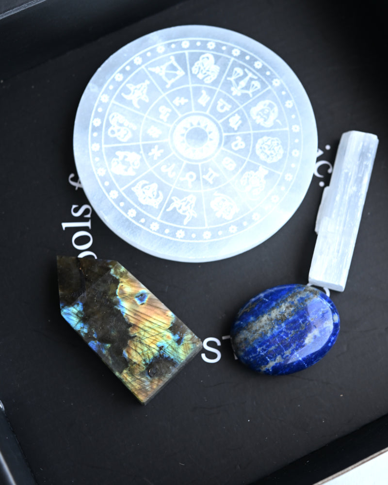 Crystal grid with stones and a wheel of the zodiac on a black surface