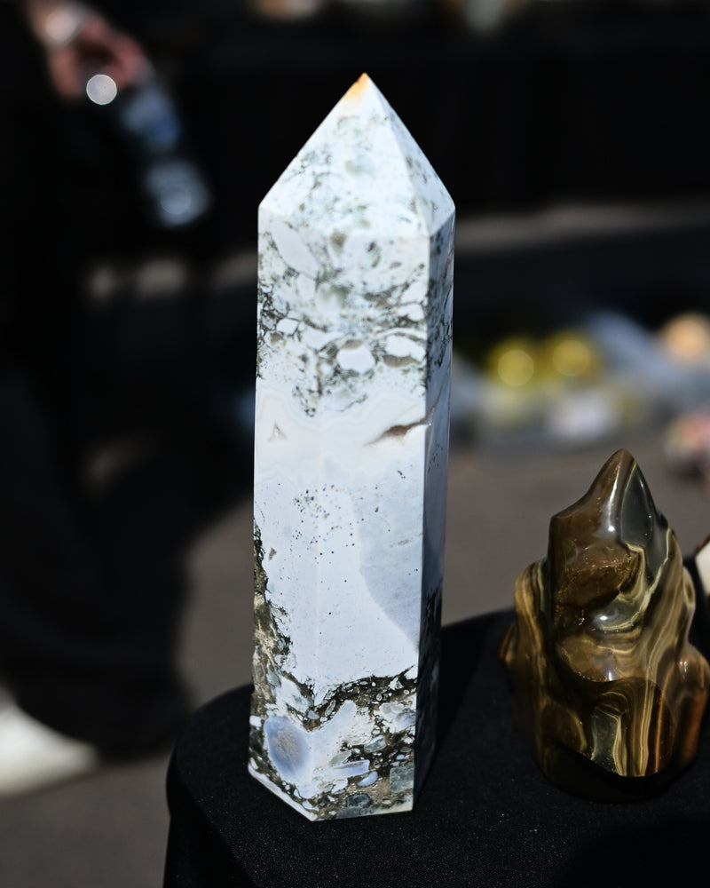 Crystal tower and tiger eye crystal on a black surface with a blurred background