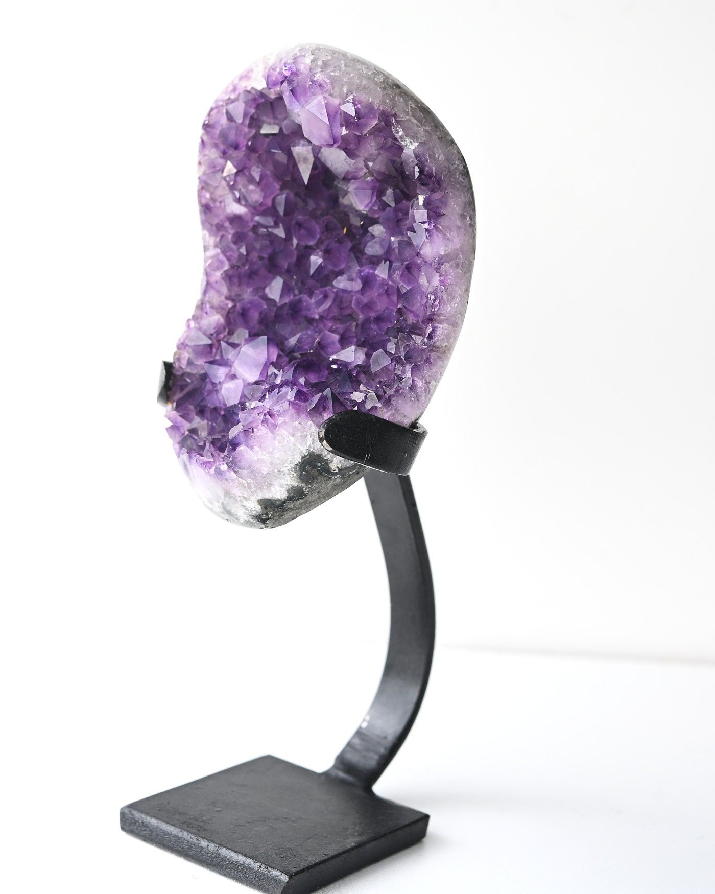 Amethyst geode on metal stand showing deep purple crystal points