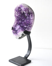 Amethyst geode on metal stand showing deep purple crystal points