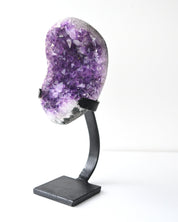 Amethyst geode cluster on black iron display stand, front view