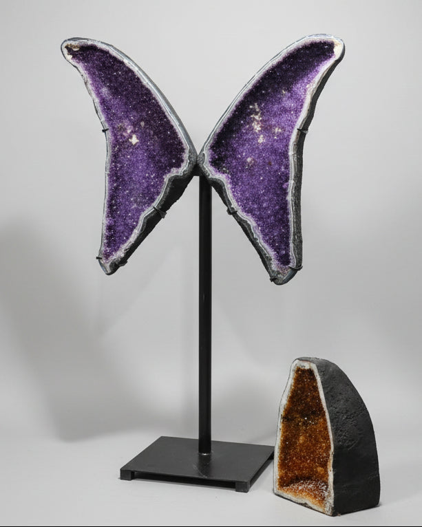 Butterfly-shaped purple crystal on a stand with a white background