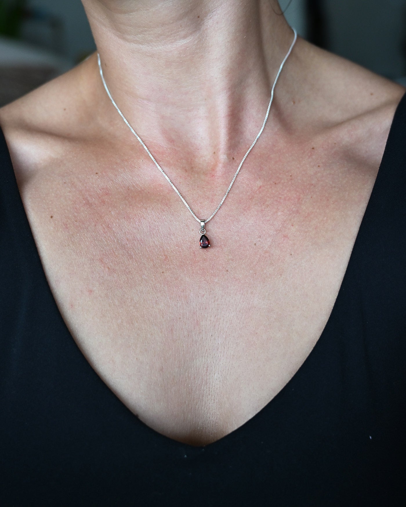 Pear-cut garnet pendant necklace on model, 925 sterling silver
