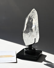 Clear crystal on a black stand against a dark background