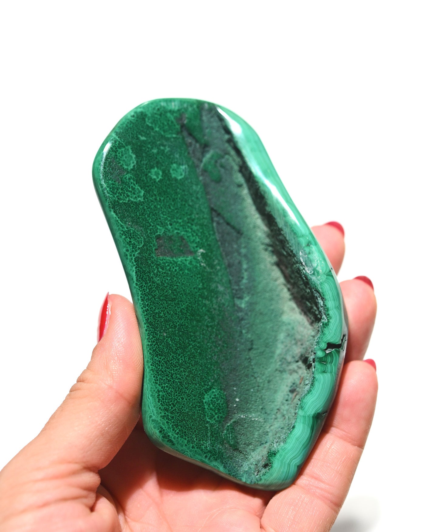 Malachite freeform held in hand for scale