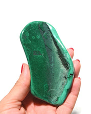 Malachite freeform held in hand for scale