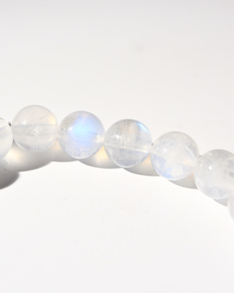 Rainbow moonstone beaded bracelet flat lay — 6mm milky white gemstone beads with blue flash