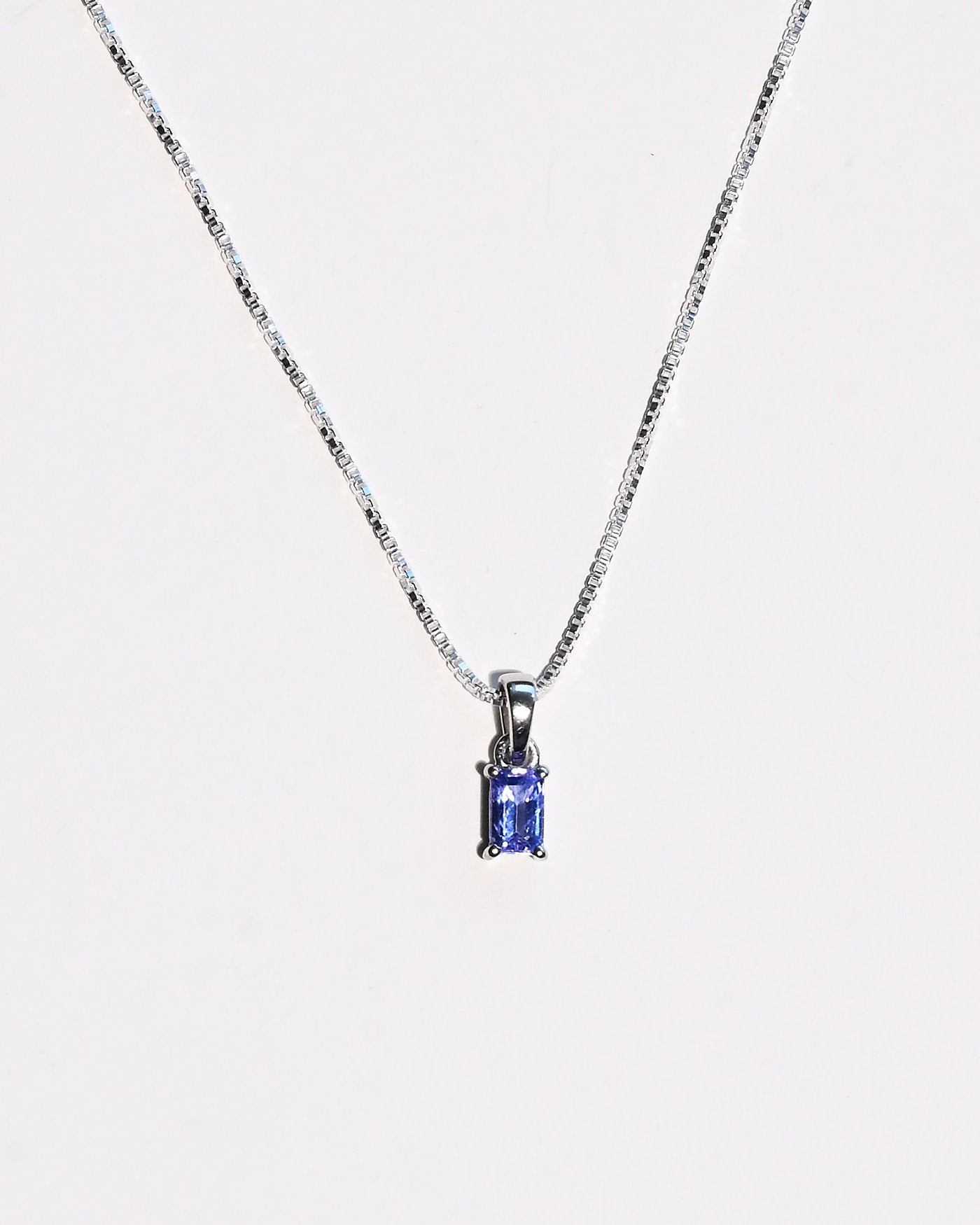 Emerald-cut tanzanite necklace styled flat lay
