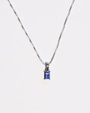 Emerald-cut tanzanite necklace styled flat lay