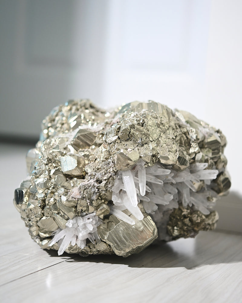 A large cluster of pyrite with clear quartz points, displaying a metallic and sparkling texture.