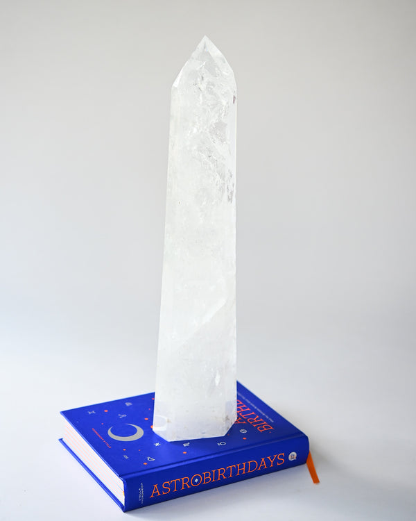 Crystal obelisk on a book titled 'Astrobirthdays' against a white background