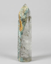 Large crystal with gold vein on a blue tablecloth, surrounded by other crystals.