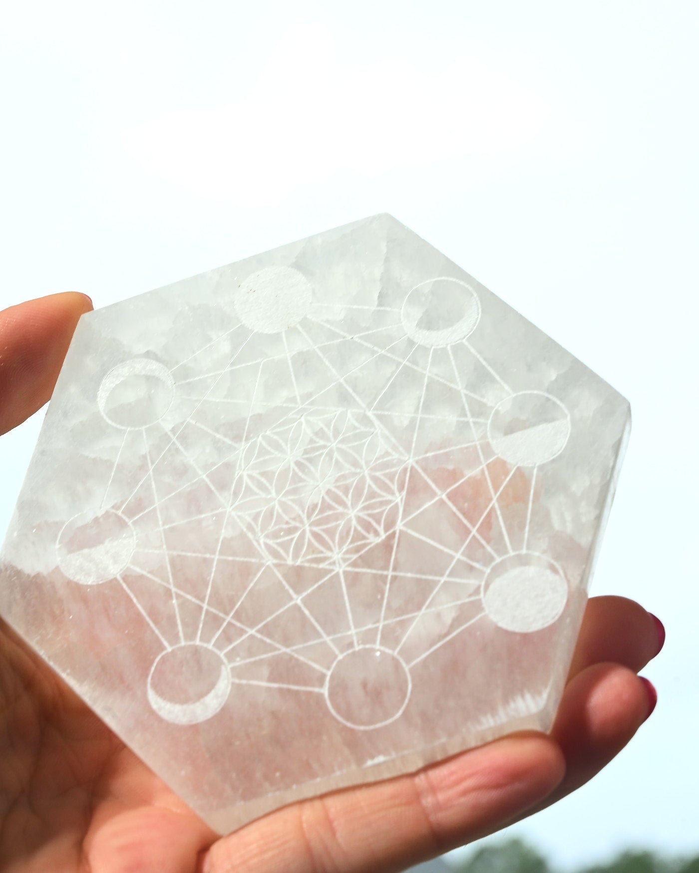 Selenite Moon Cycle Plate held in hand showing sacred geometry and moon phase engraving