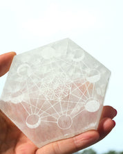 Selenite Moon Cycle Plate held in hand showing sacred geometry and moon phase engraving