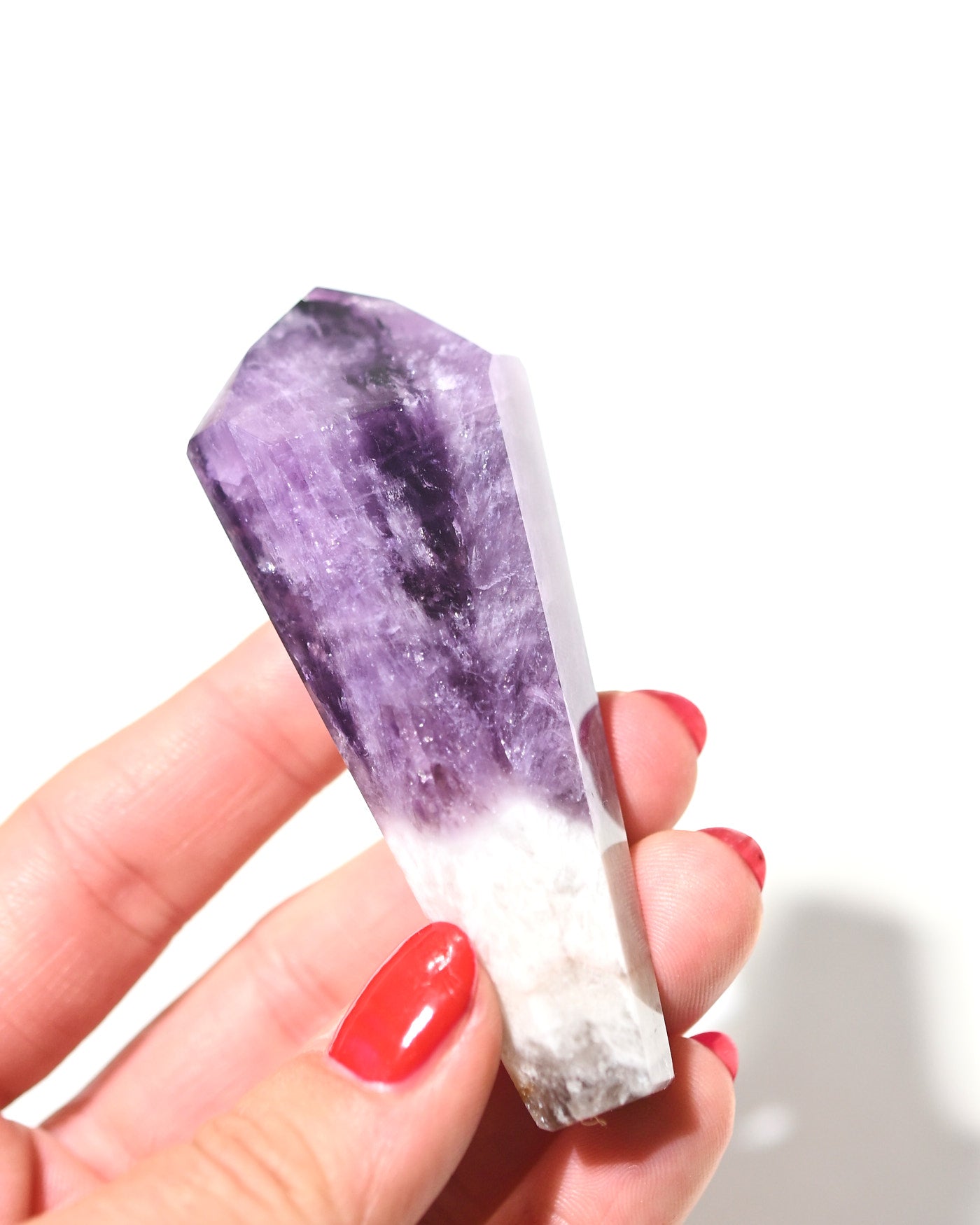 Small trapiche amethyst point with saturated purple color held in hand