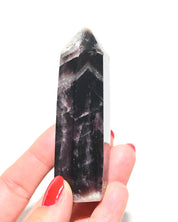 Dark trapiche amethyst point with deep violet-black color showing chevron banding