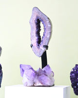 Amethyst geode on a stand against a light green background