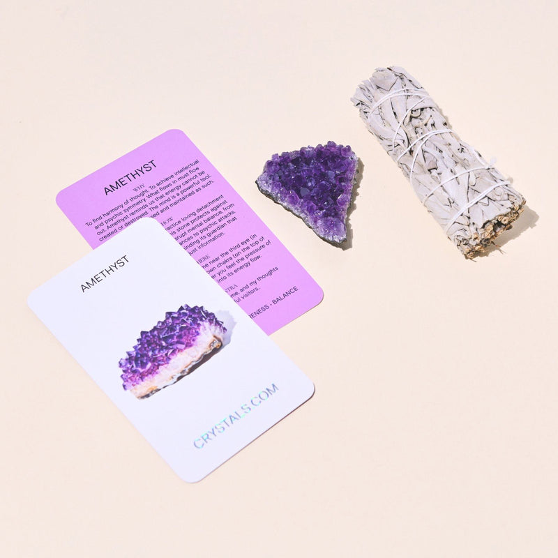 Amethyst crystal, cards, and a smudge stick on a beige background